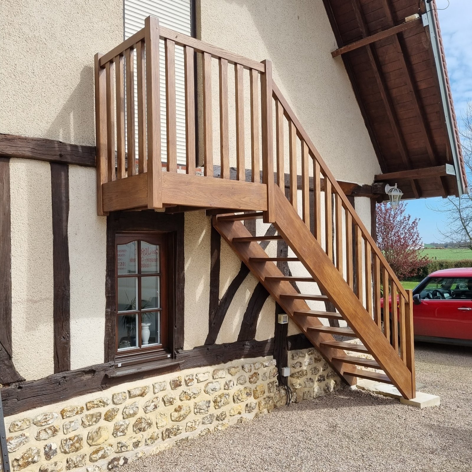 Escalier extérieur en bois menant à l'entrée d'une maison avec structure à colombages.