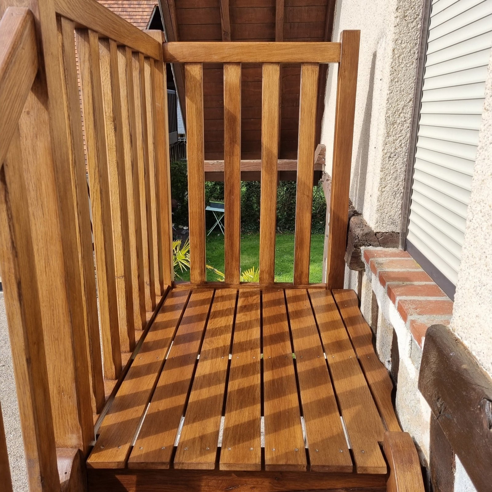 Petit balcon en bois avec balustrade en bois, attaché à une maison avec des murs en plâtre blanc.