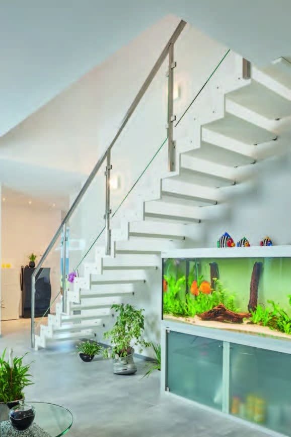 Escalier blanc modulaire avec garde-corps en verre et aquarium intégré dans un salon moderne