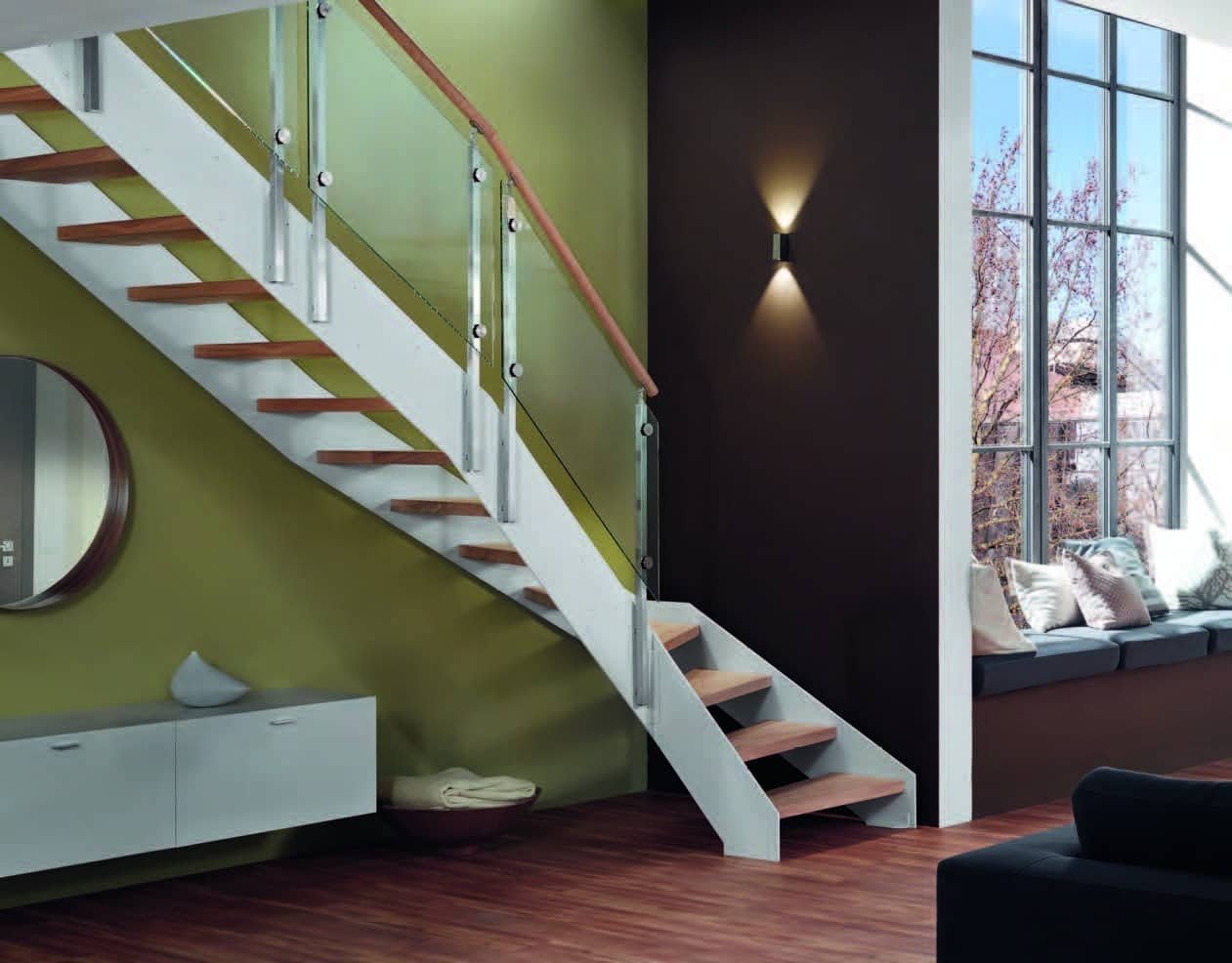 Escalier design avec des marches en bois et une rampe en verre, situé dans un intérieur moderne avec une grande verrière offrant une vue sur l'extérieur.