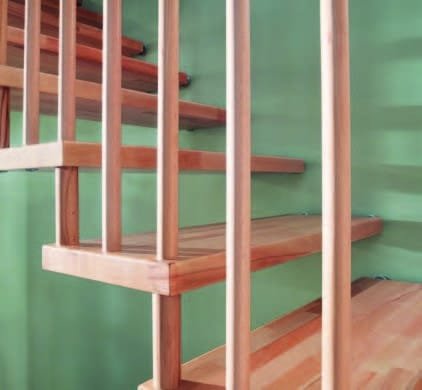 Détail d'un escalier en bois avec garde-corps assorti, contre un mur vert