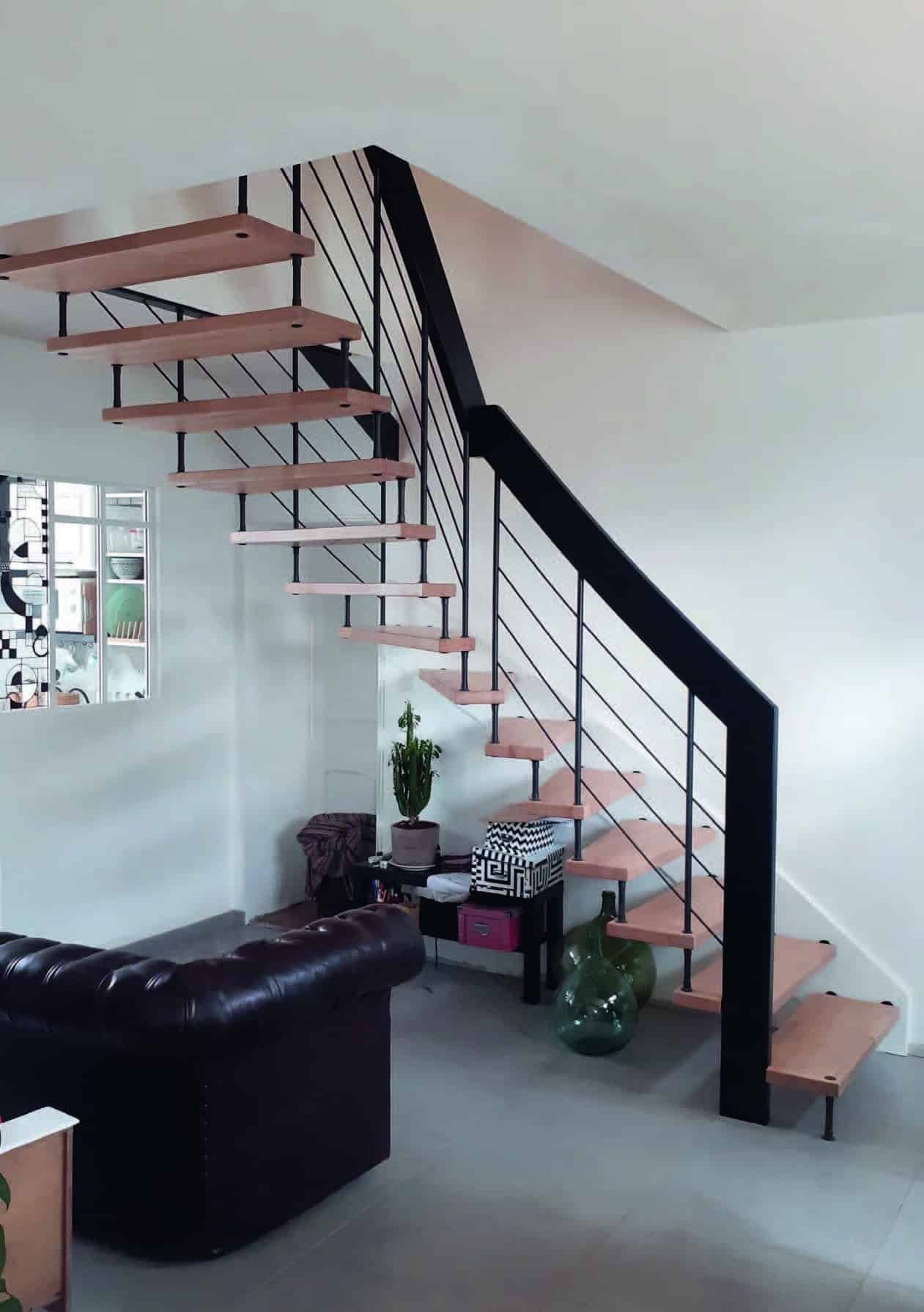 Escalier design avec des marches en bois et une structure en métal noir, installé dans un salon moderne et épuré.