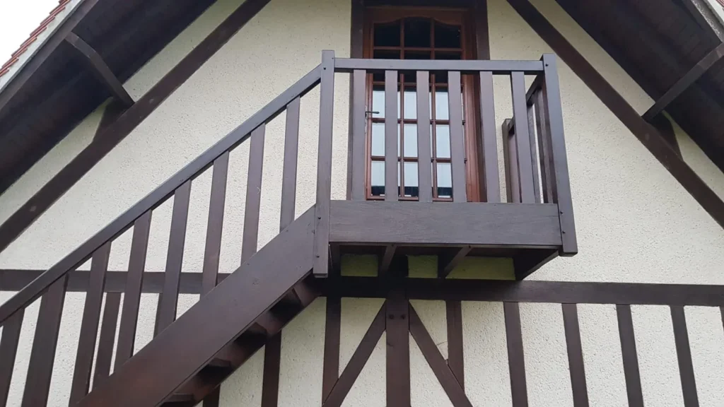 Escalier extérieur et balcon en bois sur une maison à colombages