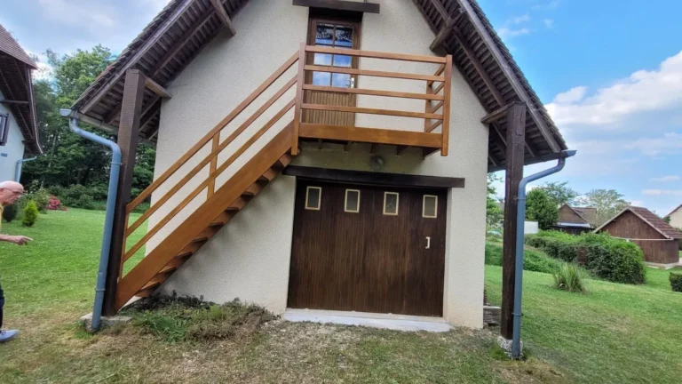 Escalier extérieur en bois avec balcon sur une maison normande