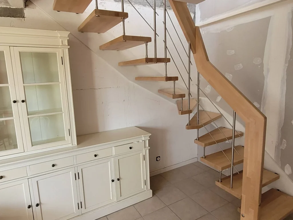 Escalier à marches en bois sur limon métal à côté d'un buffet blanc