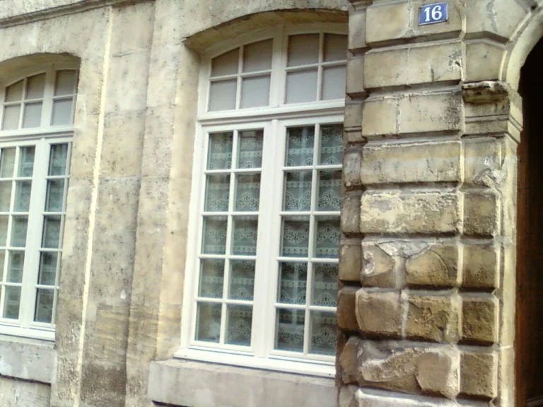 Fenêtre en bois à petits carreaux posée dans une façade en pierre