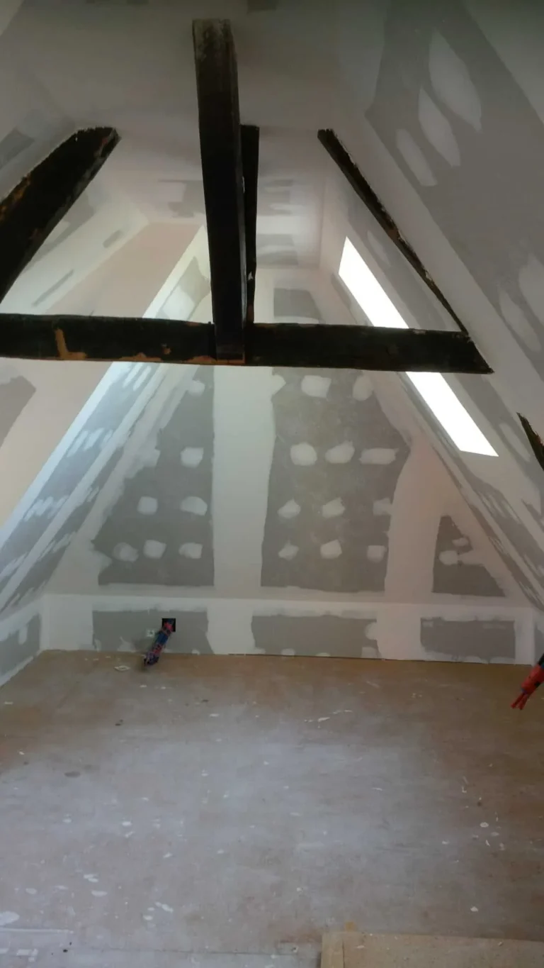 Combles en cours d'aménagement avec charpente et plaques de plâtre