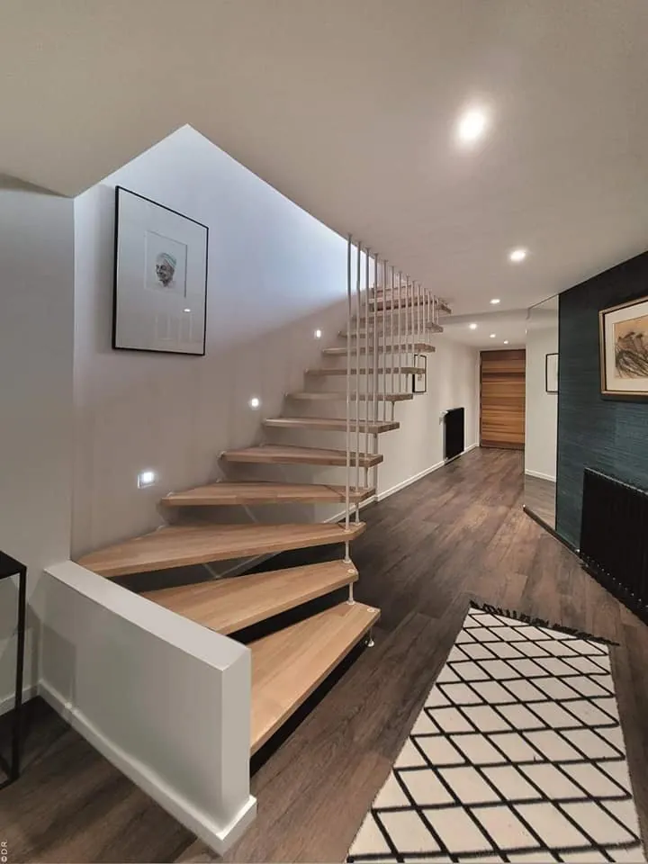 Escalier suspendu en bois clair éclairé par des spots dans les marches