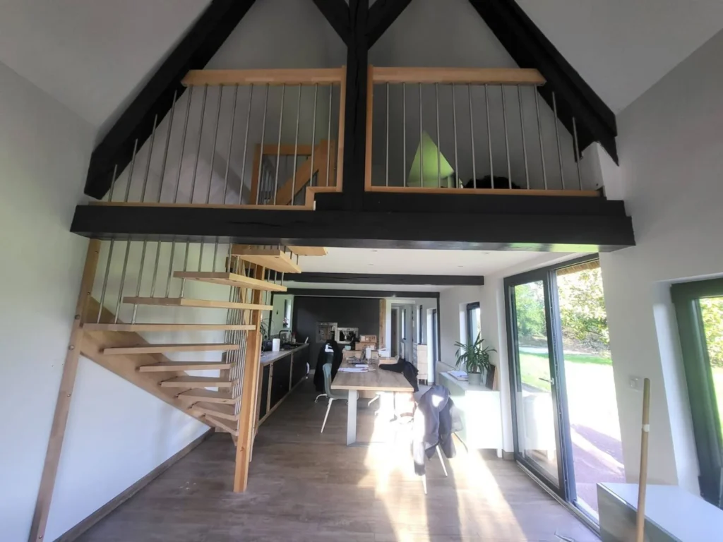 Escalier à marches en bois menant à une mezzanine sous charpente
