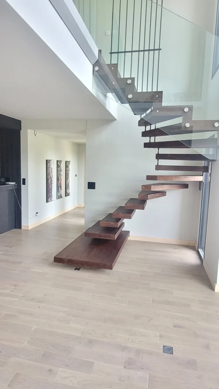 Escalier suspendu à marches en bois foncé dans un séjour lumineux
