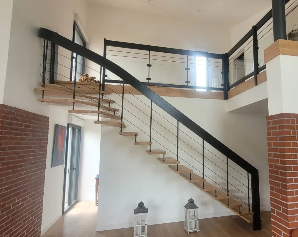 Escalier bois et métal avec garde-corps à câbles menant à une mezzanine