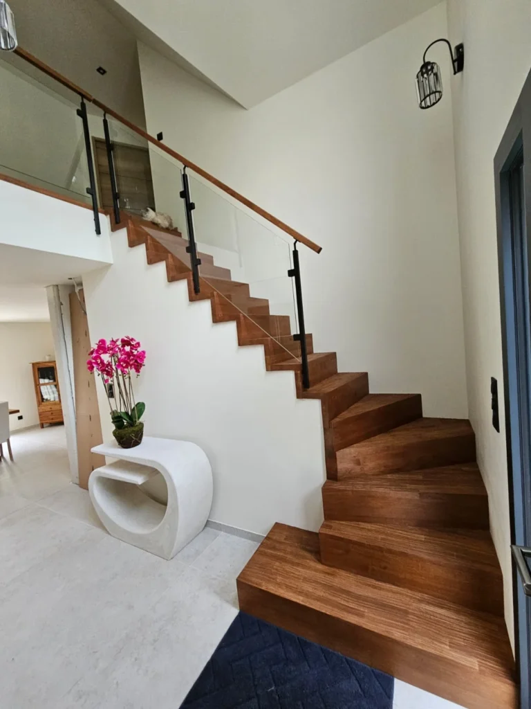 Escalier quart tournant en bois foncé dans une entrée claire